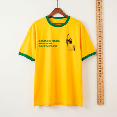 Camiseta amarela Seleção do Povo com Sócrates de punho erguido e o lema Ganhar ou perder mas sempre com democracia | Que Isso Camarada